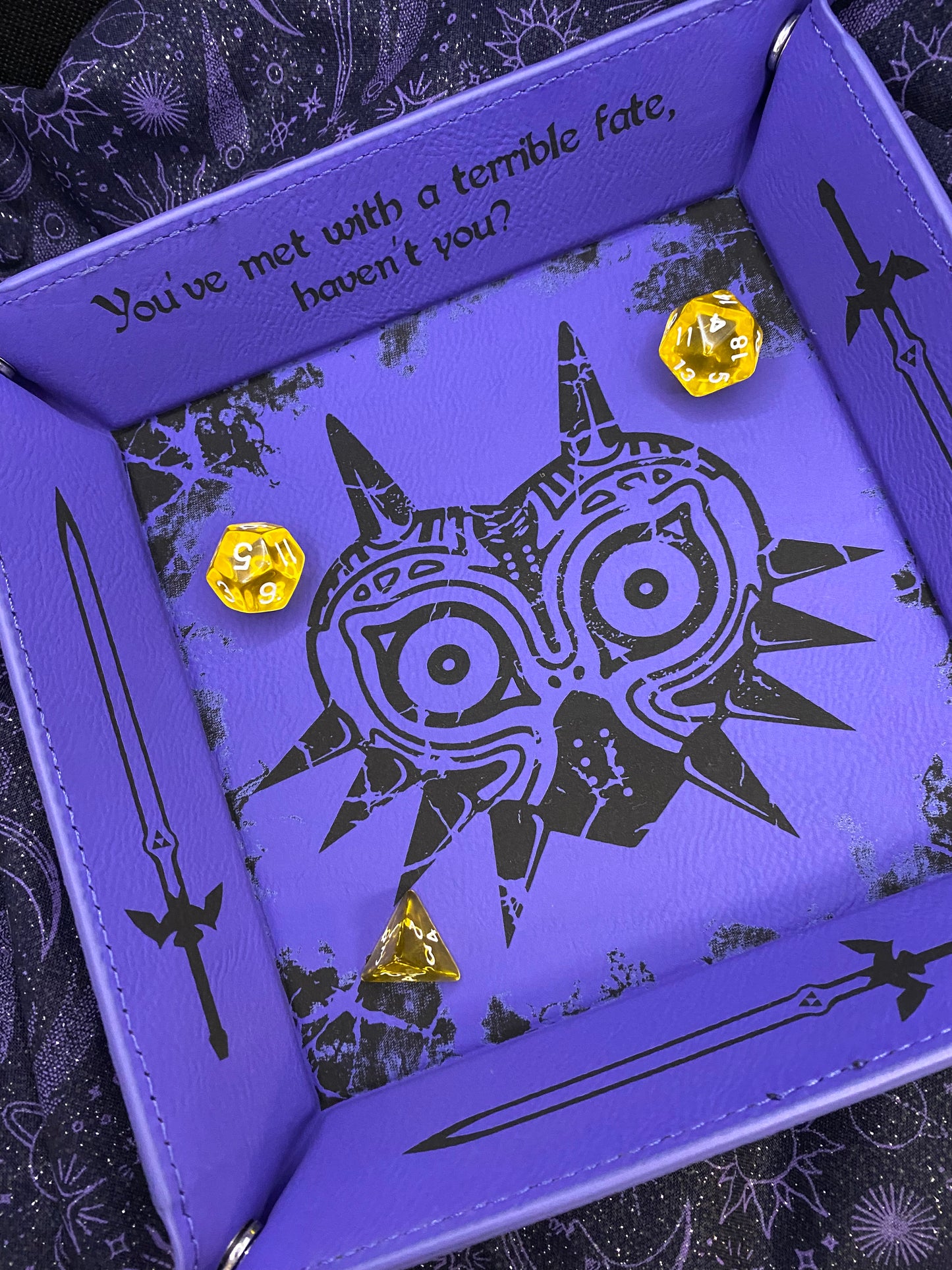 Purple leather dice tray featuring a laser engraved Majora’s Mask design and sword icons, inspired by The Legend of Zelda. Ideal for tabletop and D&D fans who love Zelda lore. Slight misprint with the master swords