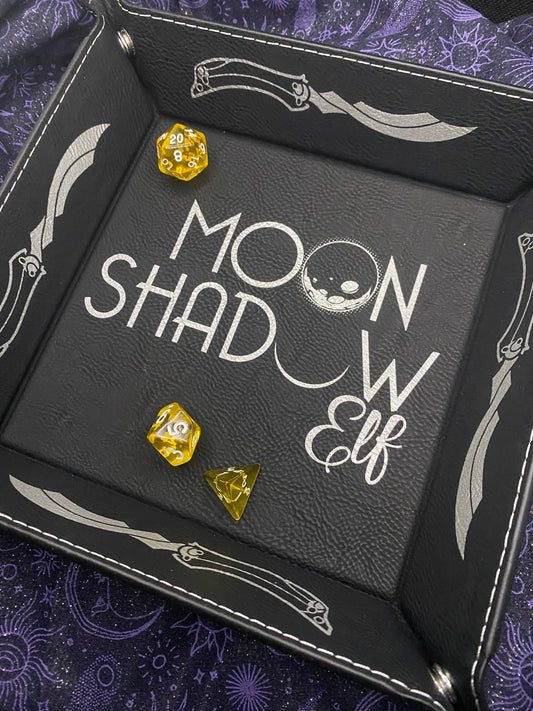 Black faux leather dice tray engraved with silver Moonshadow Elf theme, featuring daggers, moons, and elegant text, inspired by The Dragon Prince